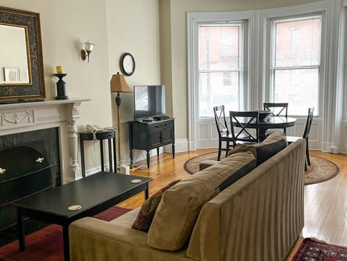 back bay boston vacation rental living room with couch, fireplace, dining table and chairs.